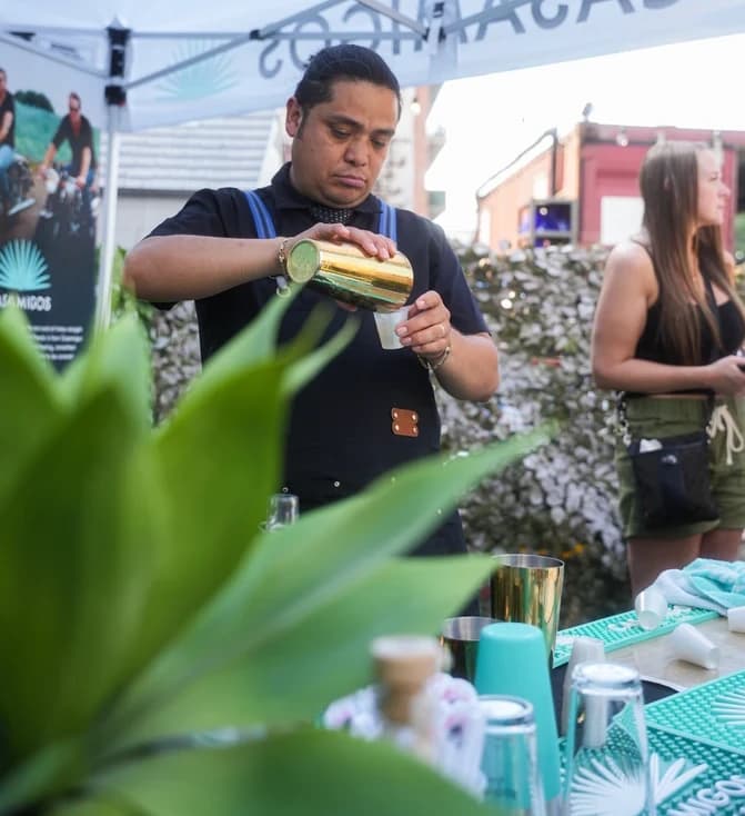 Bartender pouring a cocktail at an outdoor food festival booth