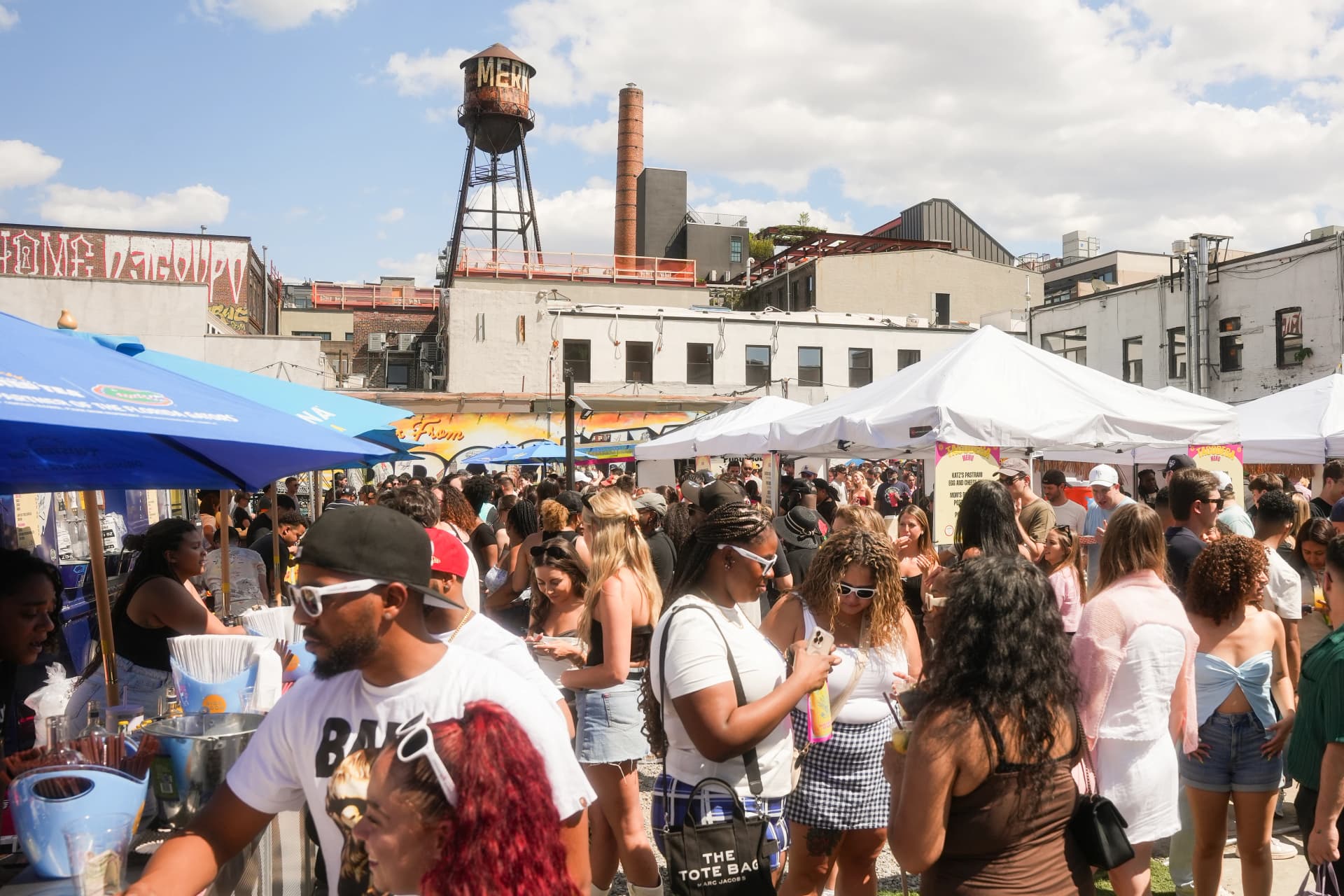 Crowds filling a bustling outdoor food festival with vendor tents and umbrellas